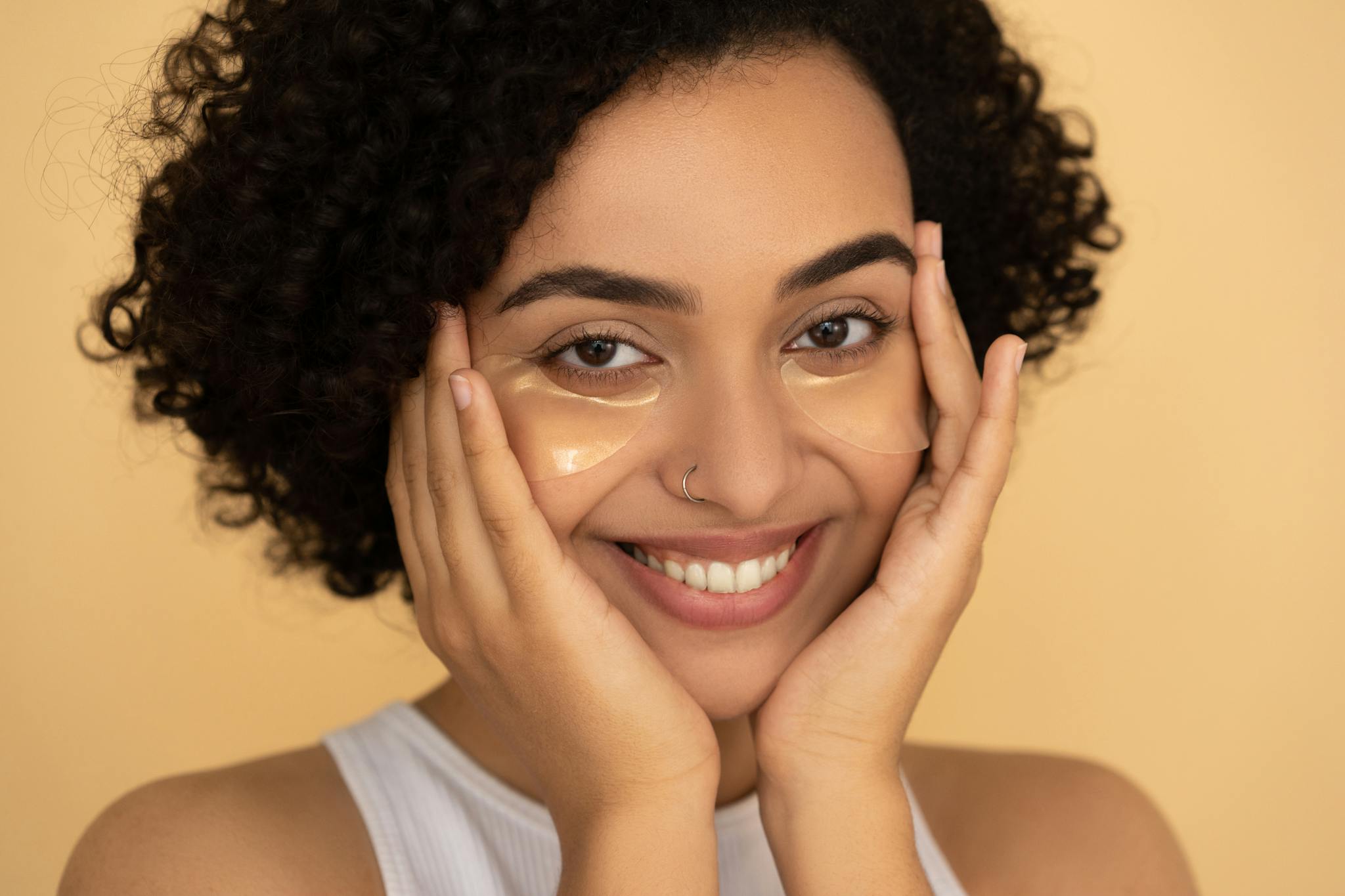 Close-up portrait of a smiling woman with under eye patches showcasing skincare routine.