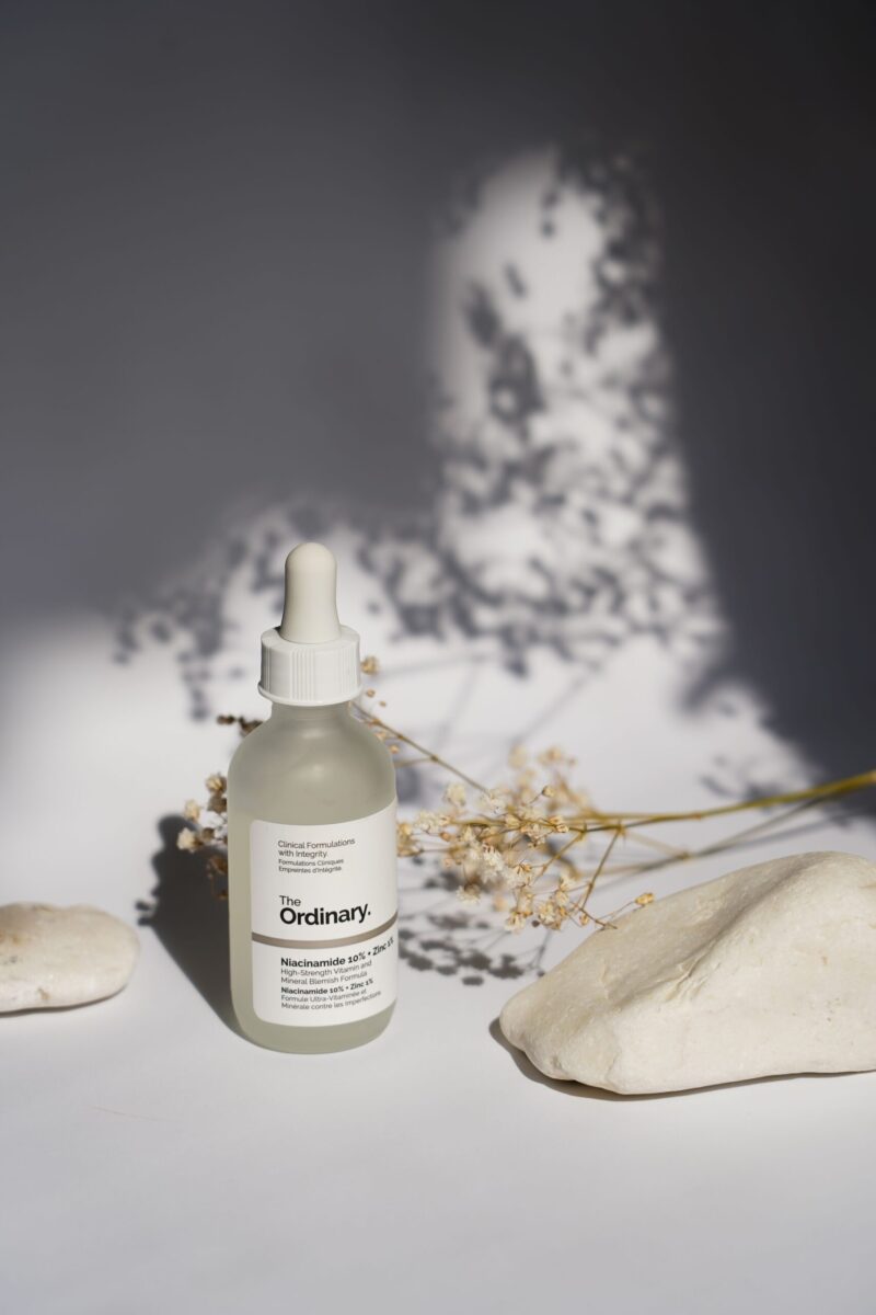 A minimalist still life of skincare serum bottle with natural shadows.